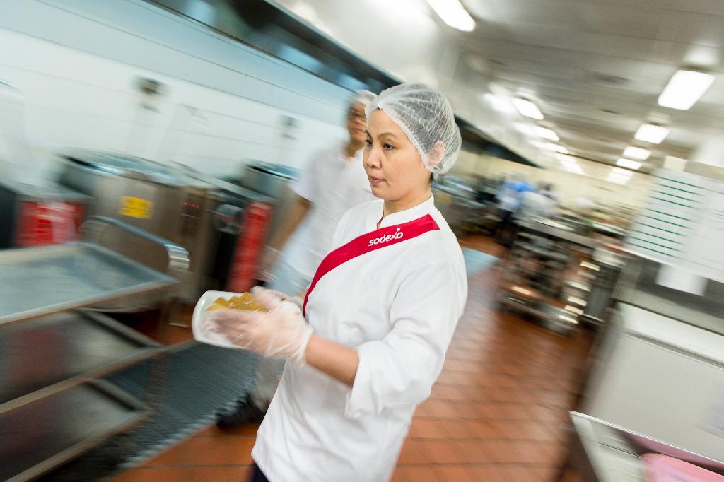 Employees wearing hairnets and masks while prepping food